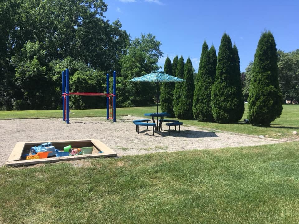 Playground with sandbox, monkey bars, and picnic table with umbrella
