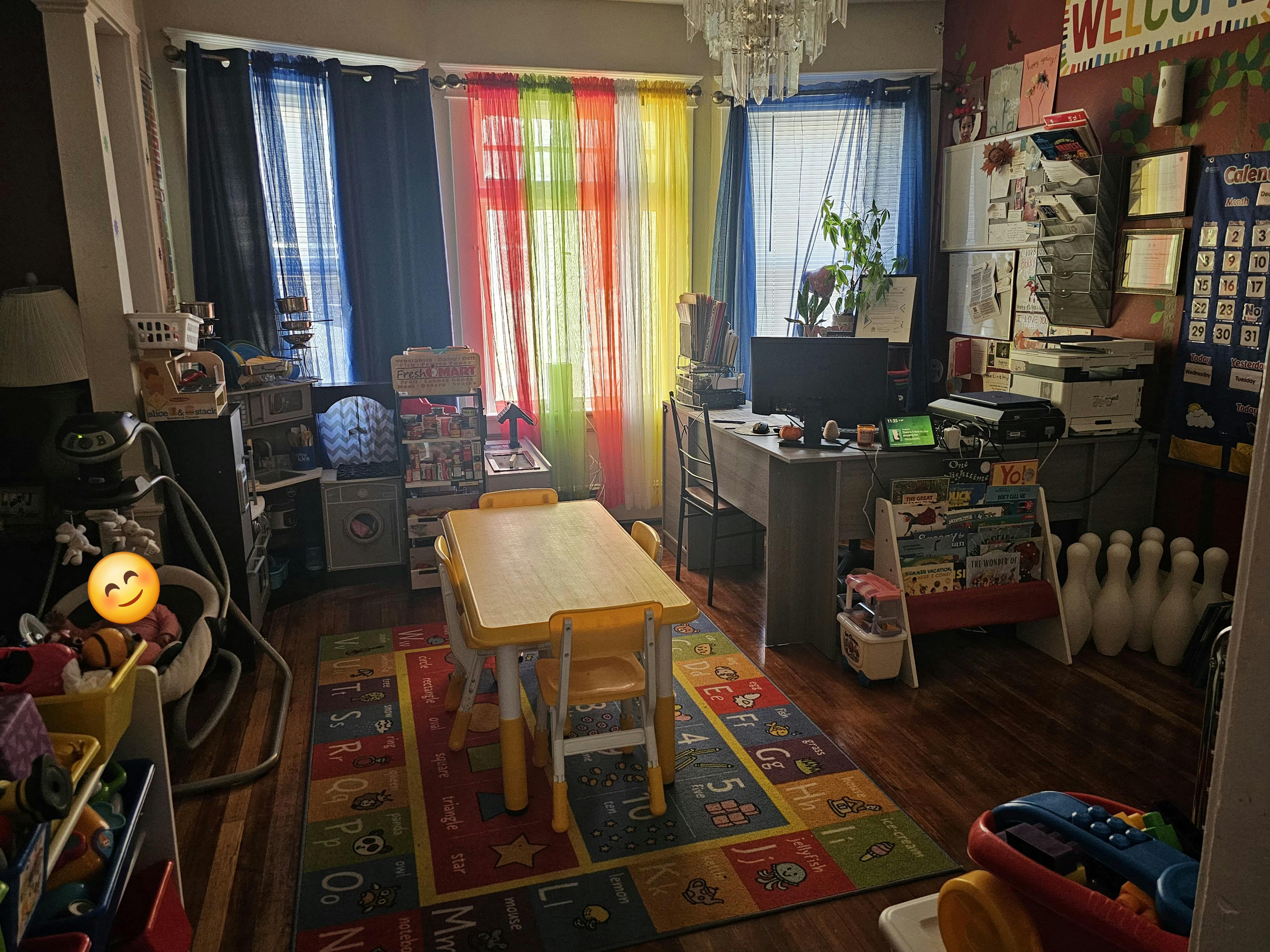 A room with a small table and chairs, colorful curtains, and a desk