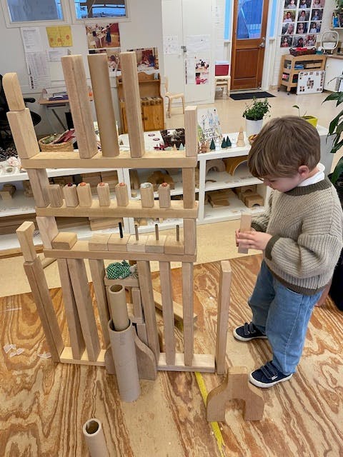 Child playing with wooden blocks in a classroom