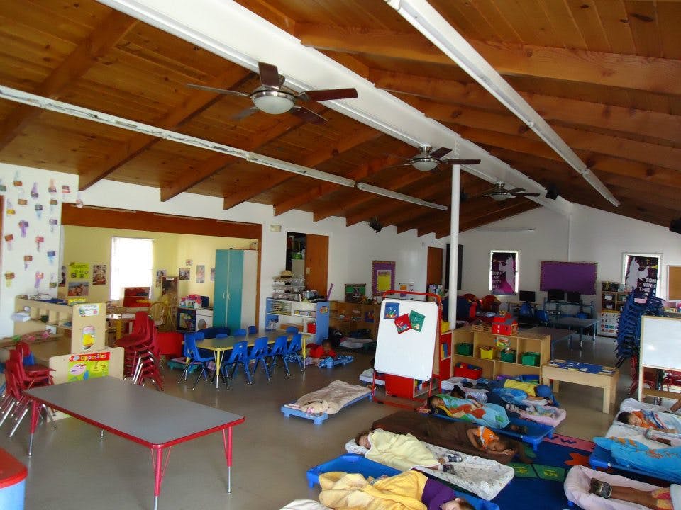 Daycare room with small tables, chairs, and sleeping mats on the floor