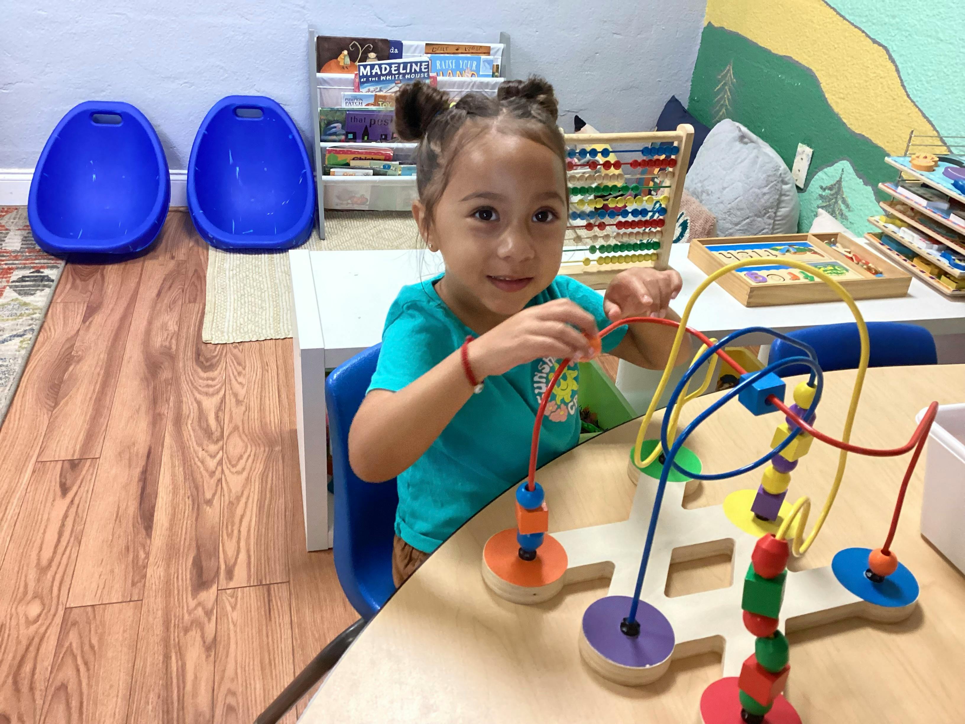 Child playing with a bead maze toy at a table