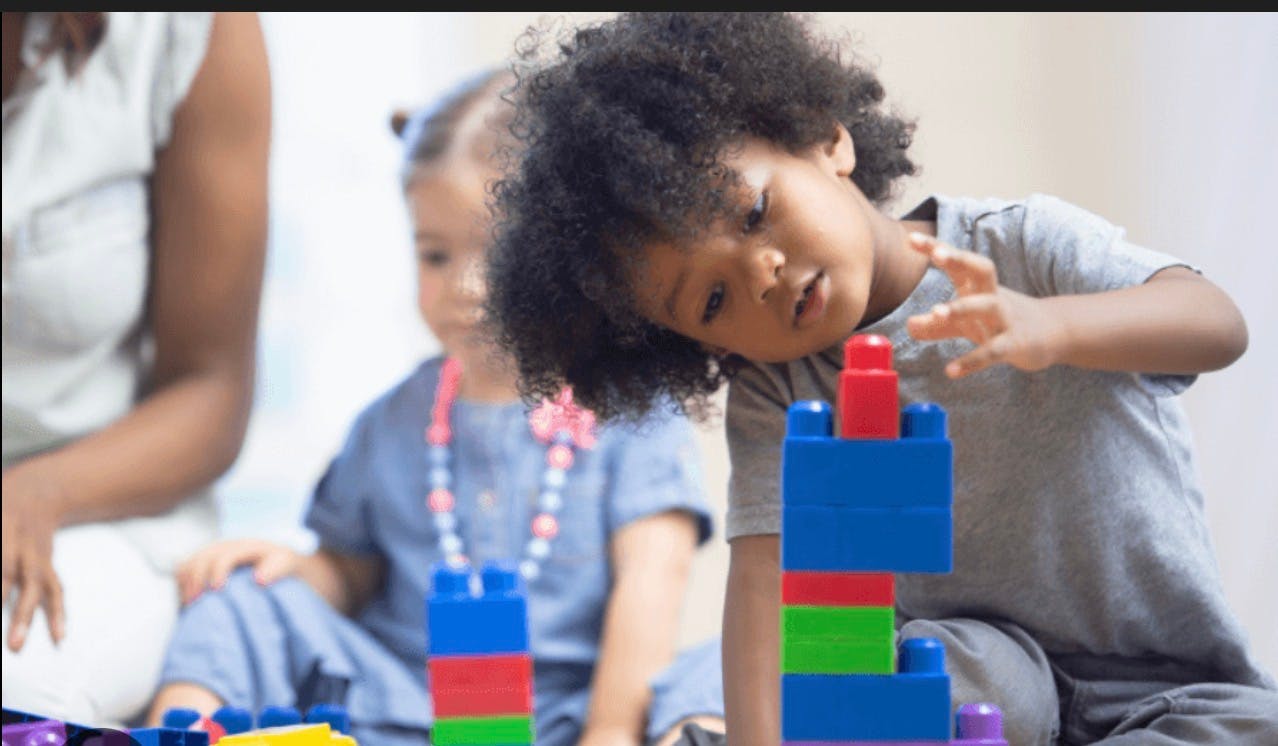 Child playing with colorful building blocks, another child in background