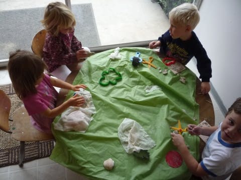 Four children playing at a table covered with a green cloth