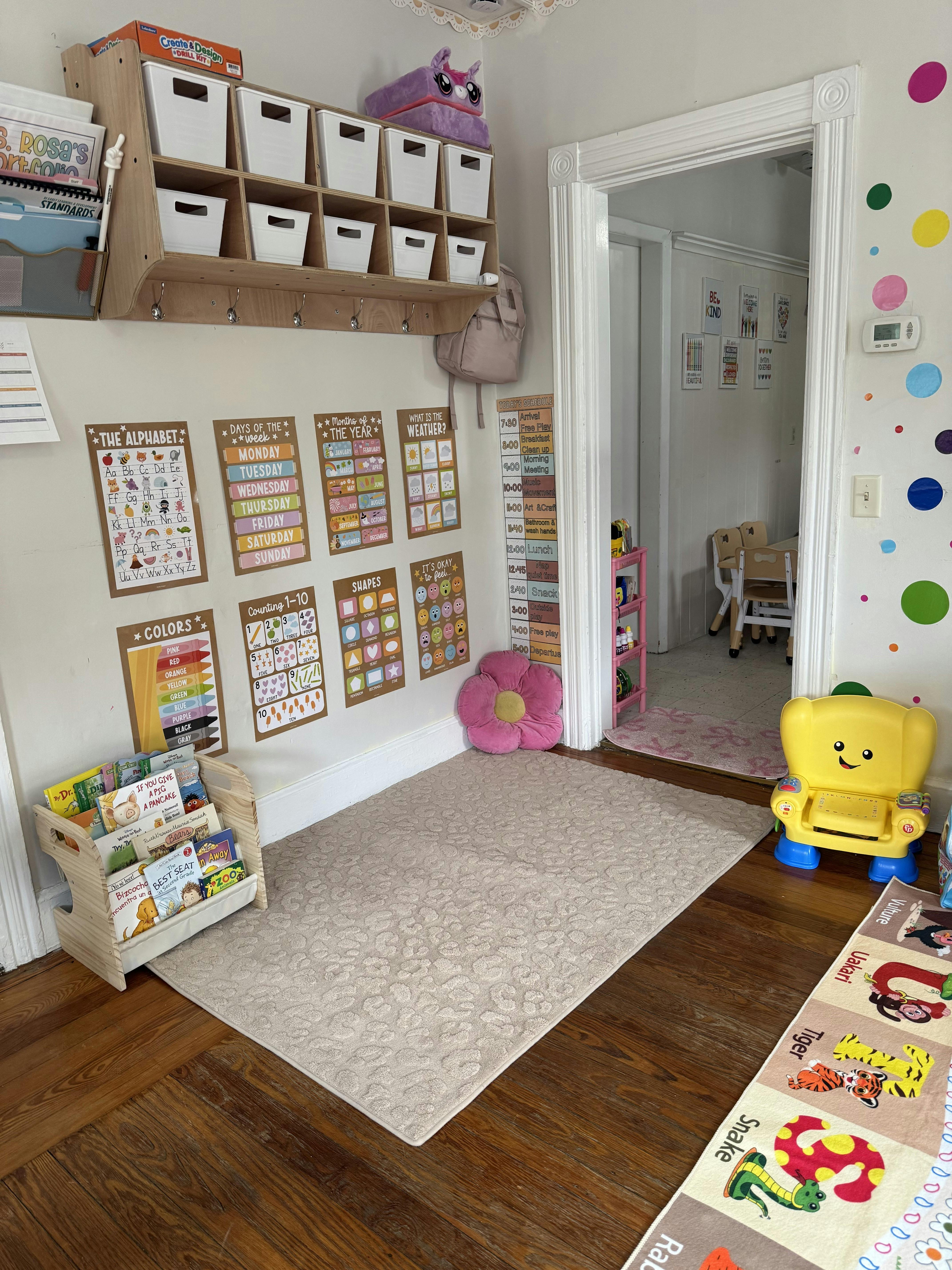 Classroom wall with educational posters, wooden book rack, and rug