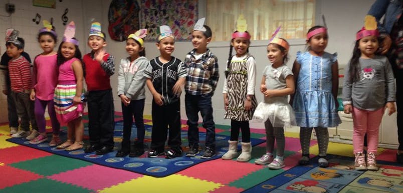 Group of children wearing paper hats standing in a classroom