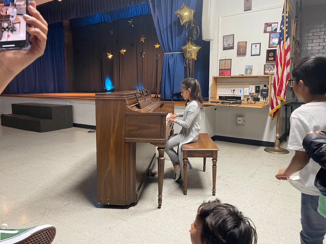 Child playing a piano on a stage