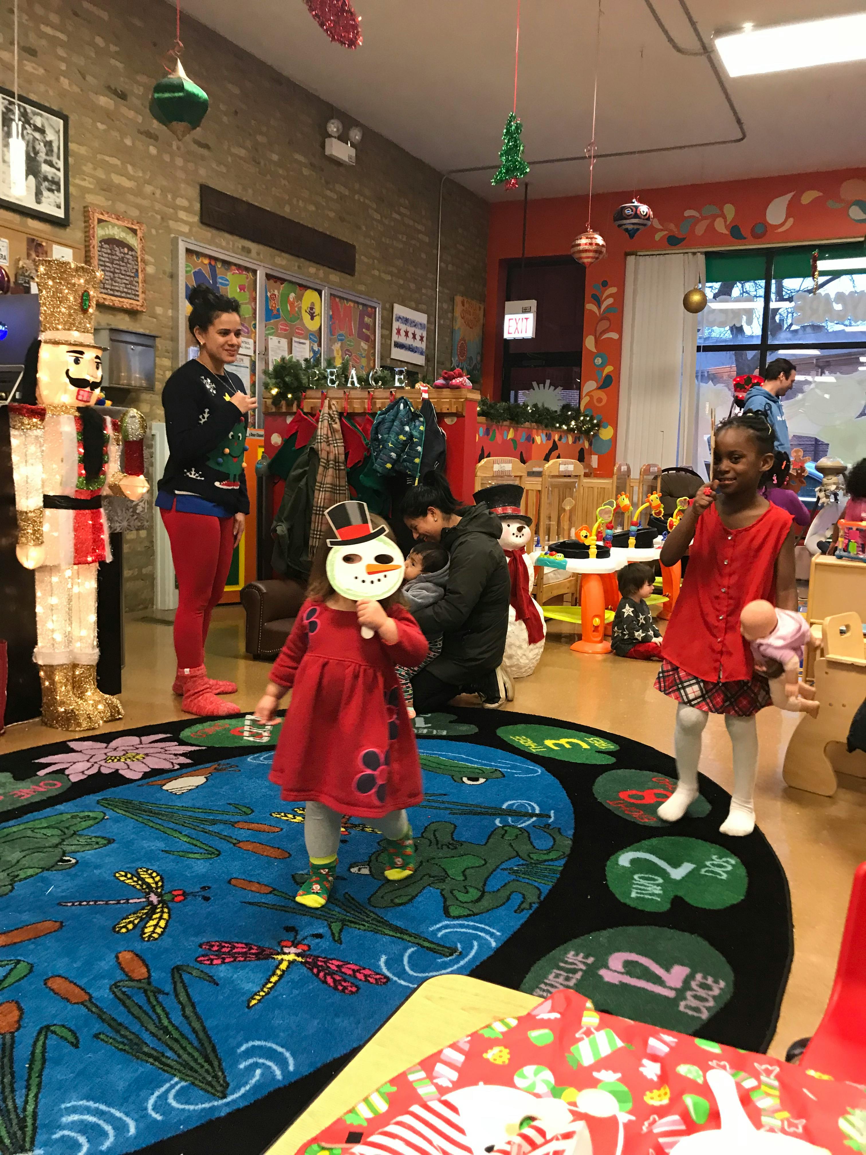 Two children and an adult in a classroom decorated for a holiday