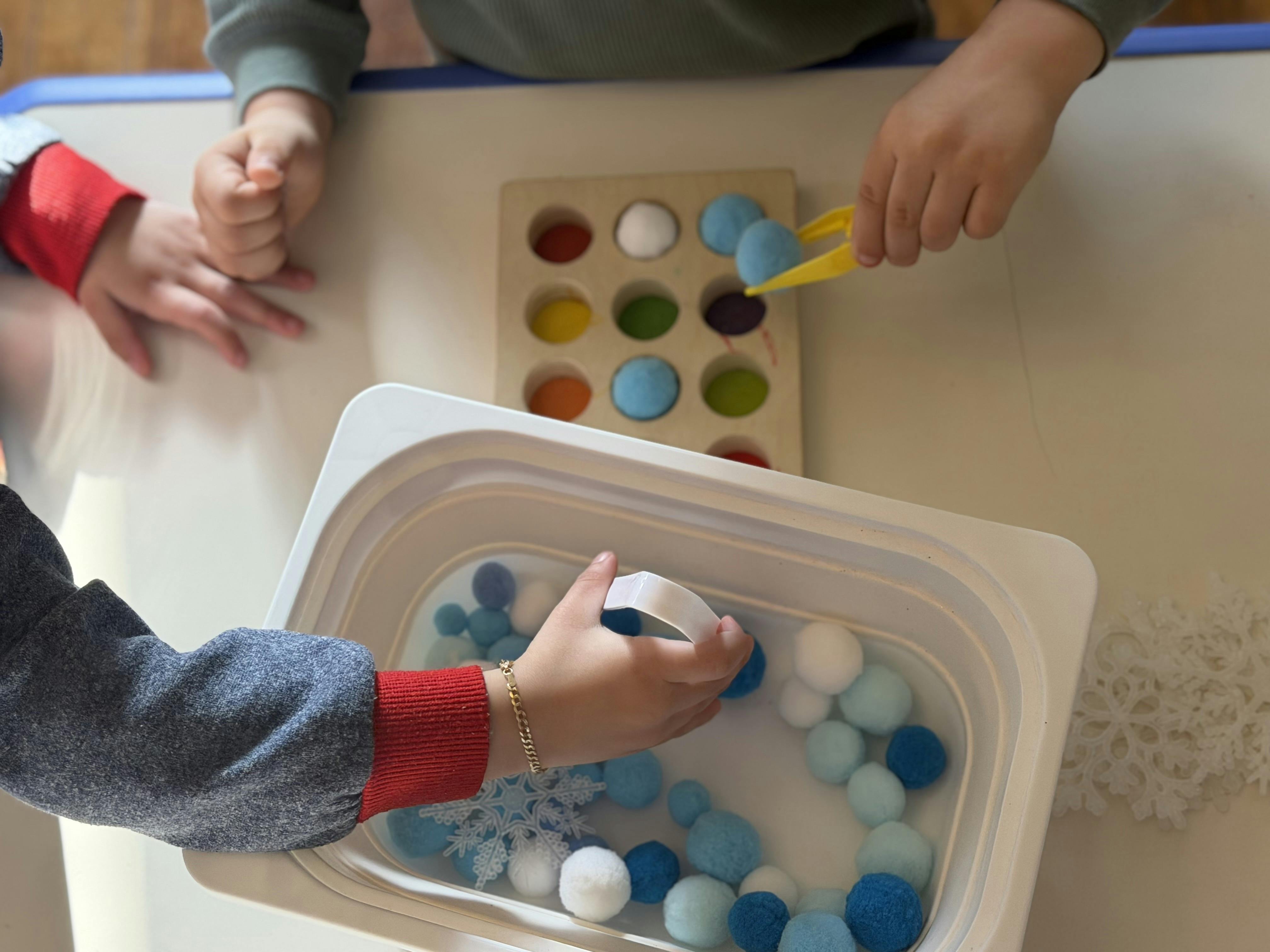 Children playing with pom-poms and a sorting tray