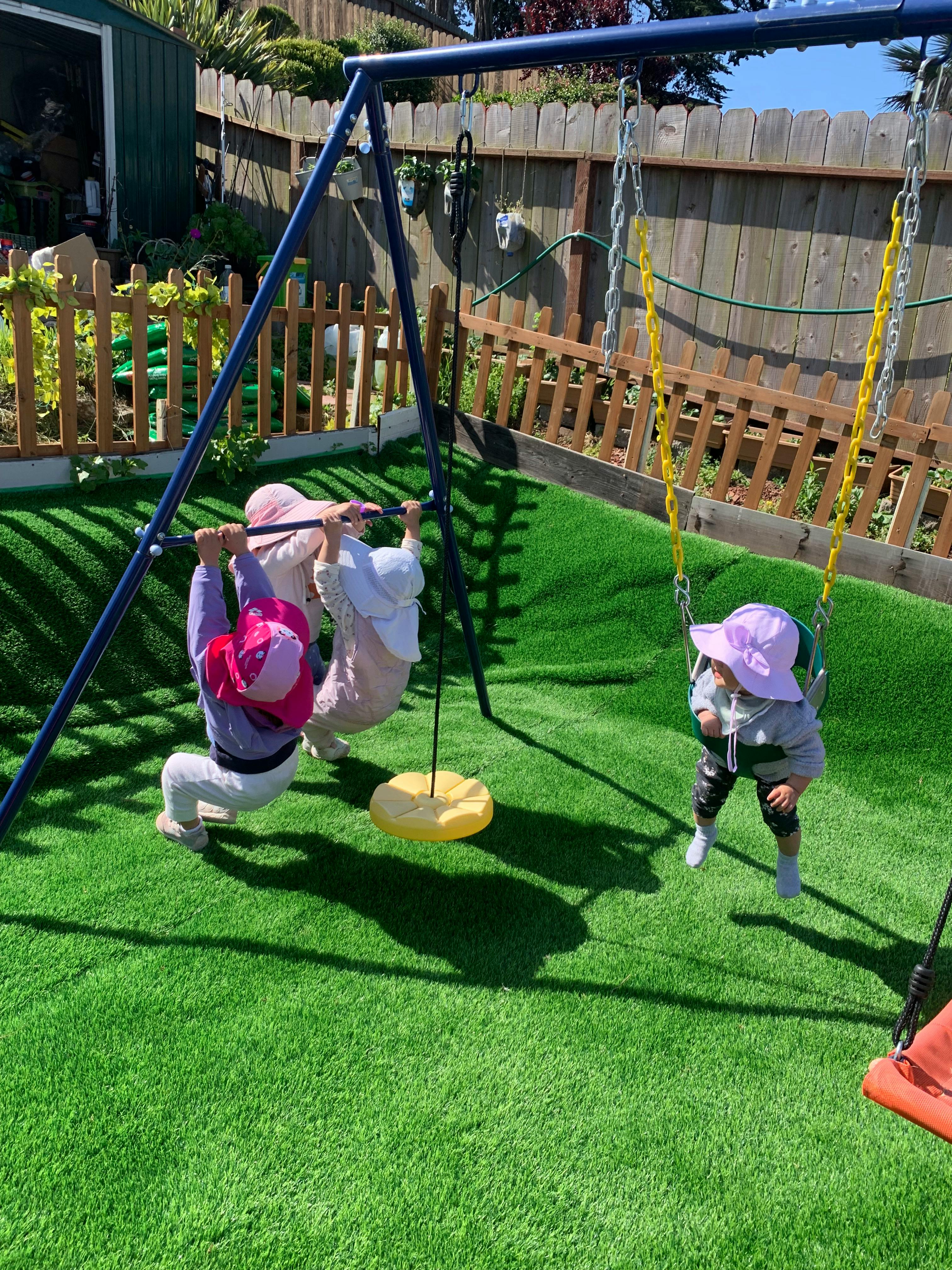 Three children playing on a swing set in a backyard