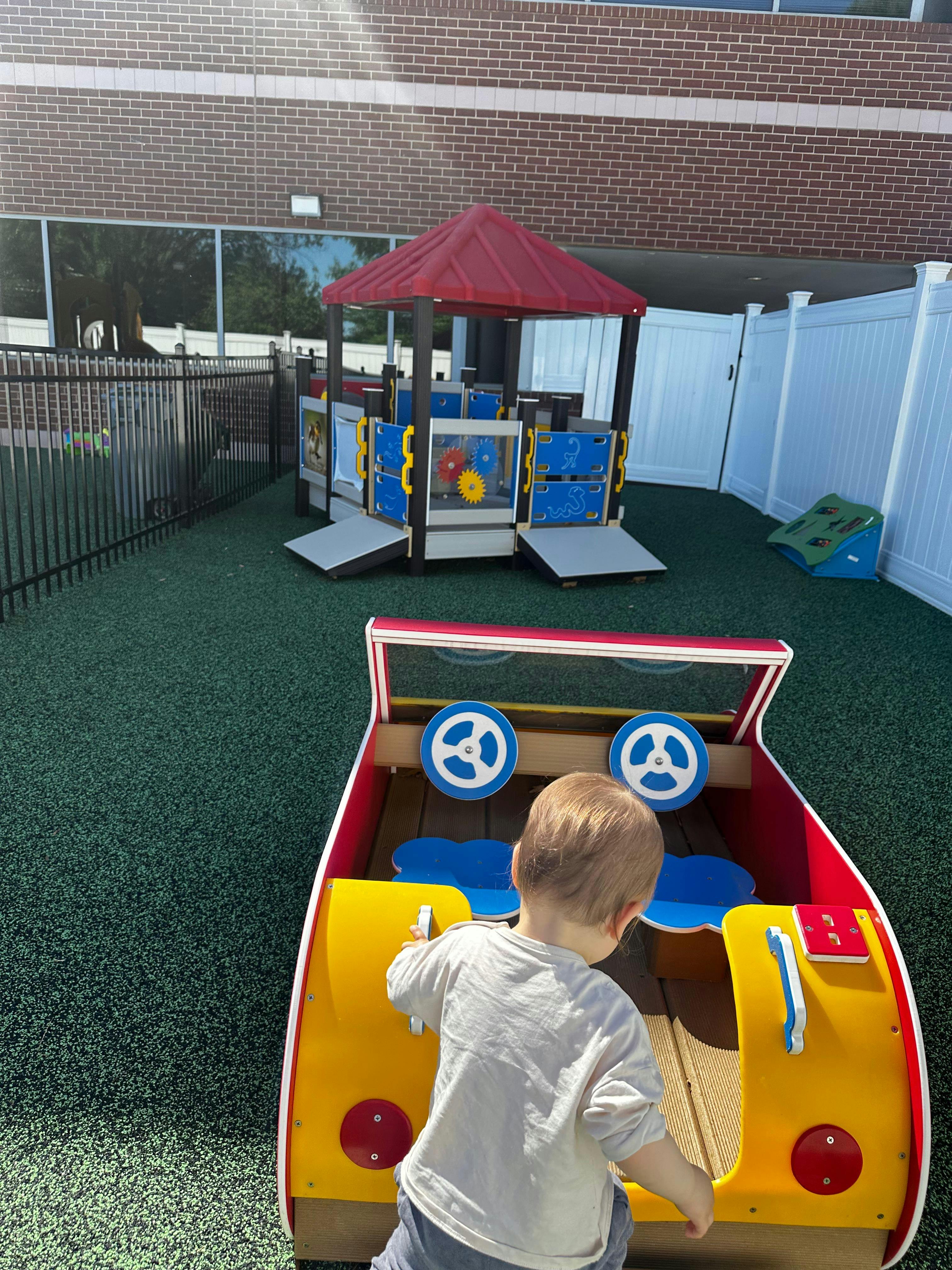 Child playing in a toy car on a playground
