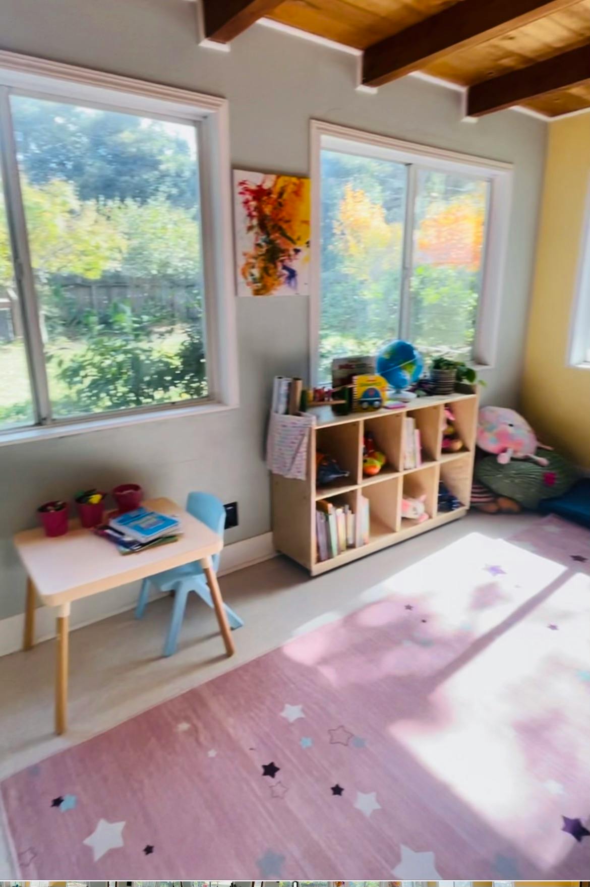 Child's room with small table and chair, bookshelf, and pink rug