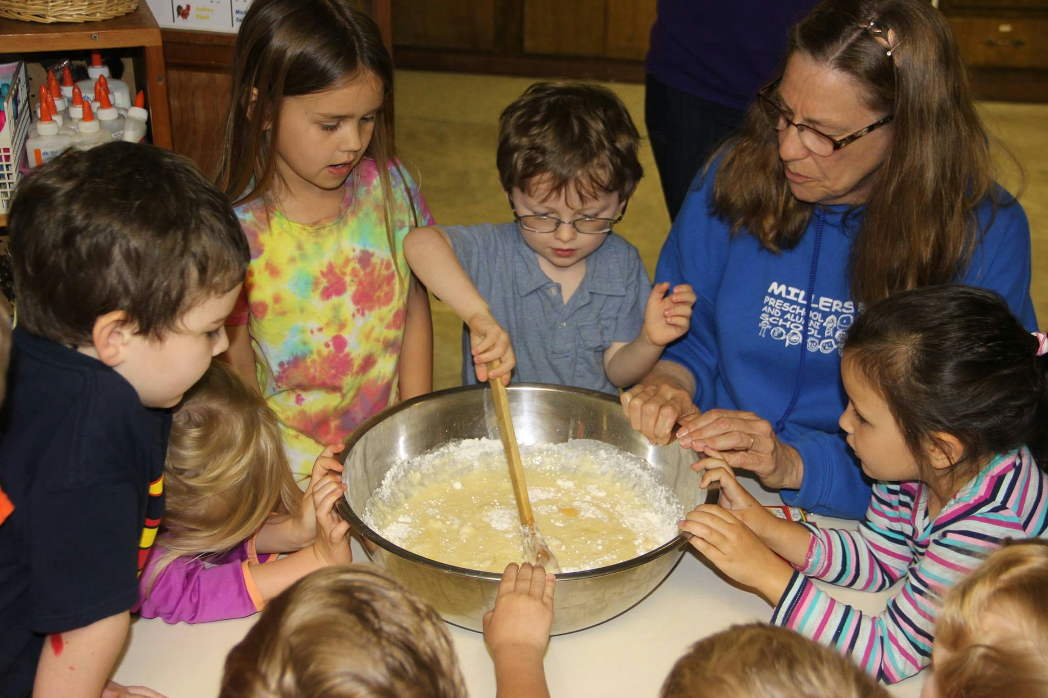 Adult and children mixing ingredients in a large bowl