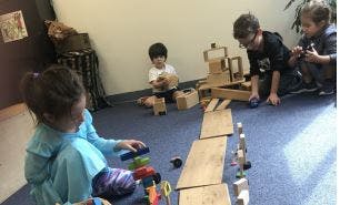 Children playing with wooden blocks and ramps on a carpeted floor