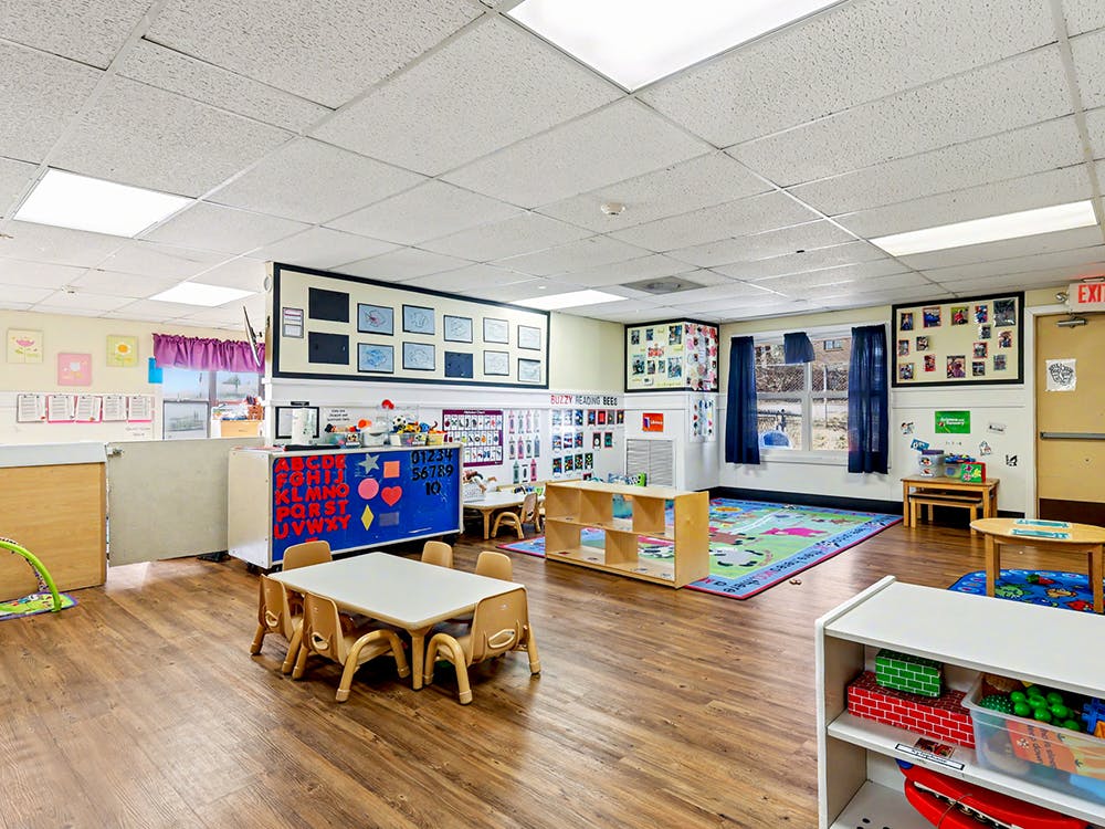 Empty preschool classroom with small tables and chairs