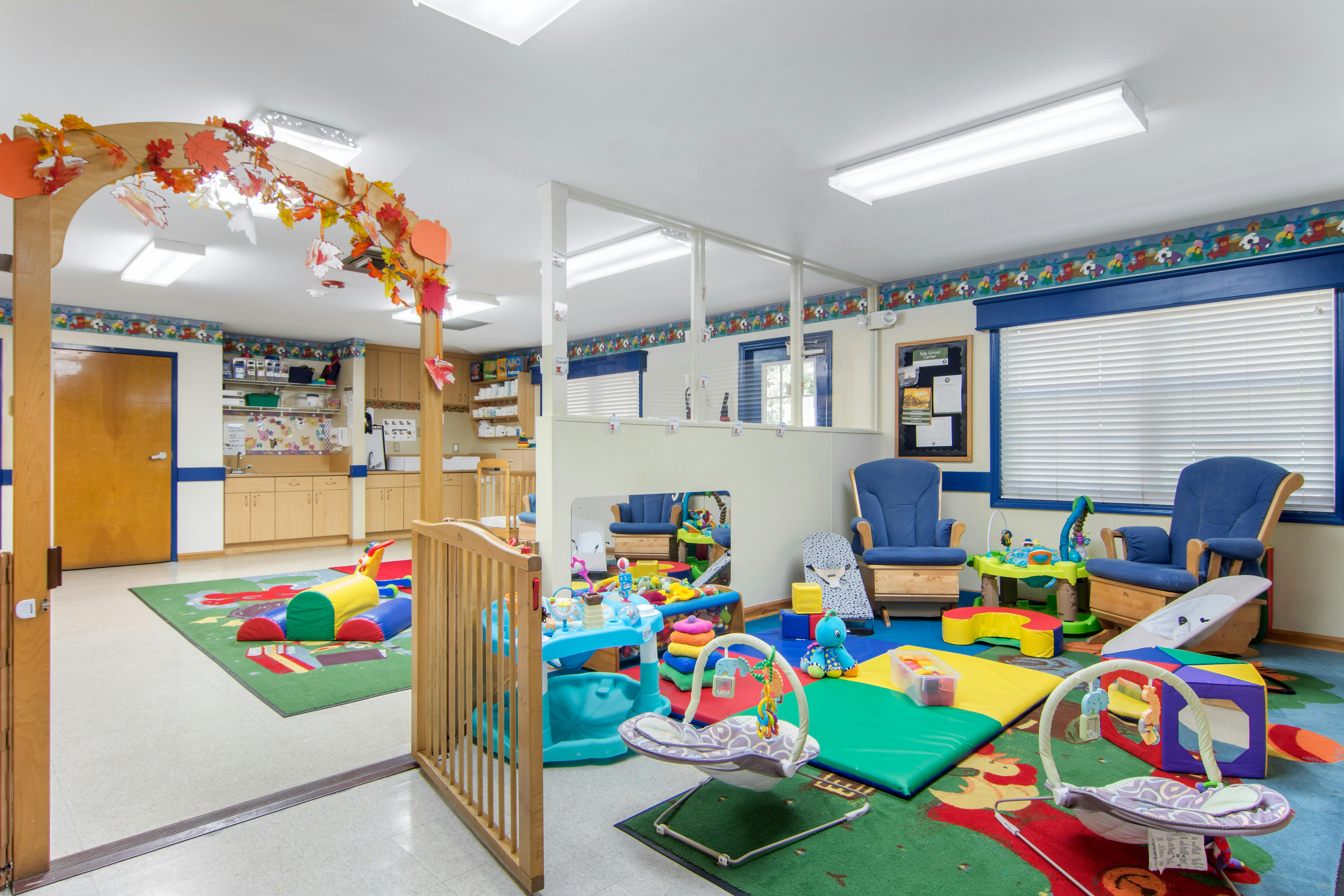 An indoor play area with bright carpets, play mats, and baby bouncers