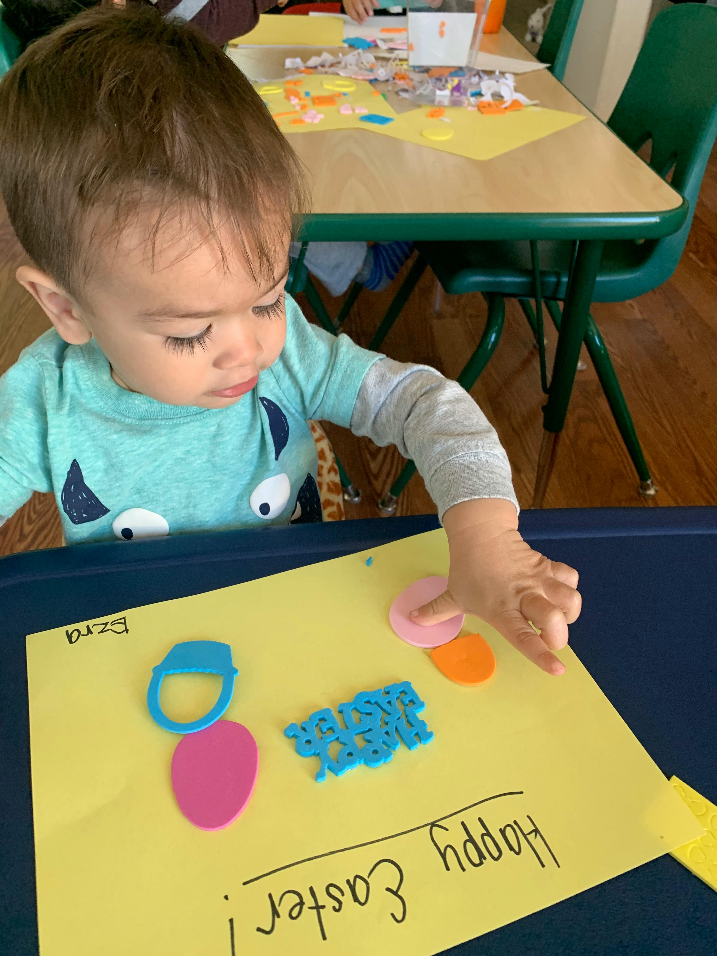 Child making a craft with paper cutouts and text "Happy Easter"