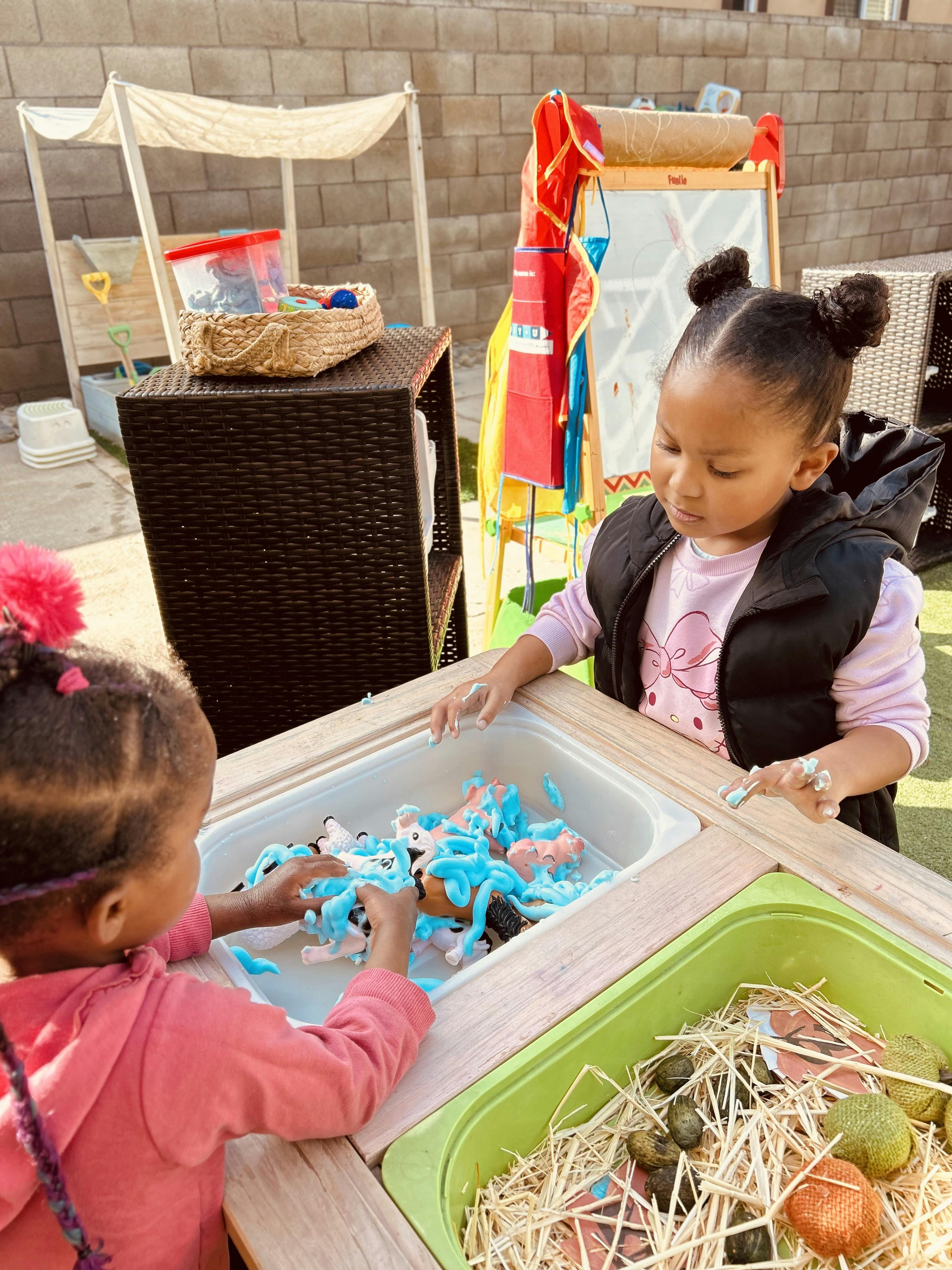 Two children playing with toy animals covered in blue foam