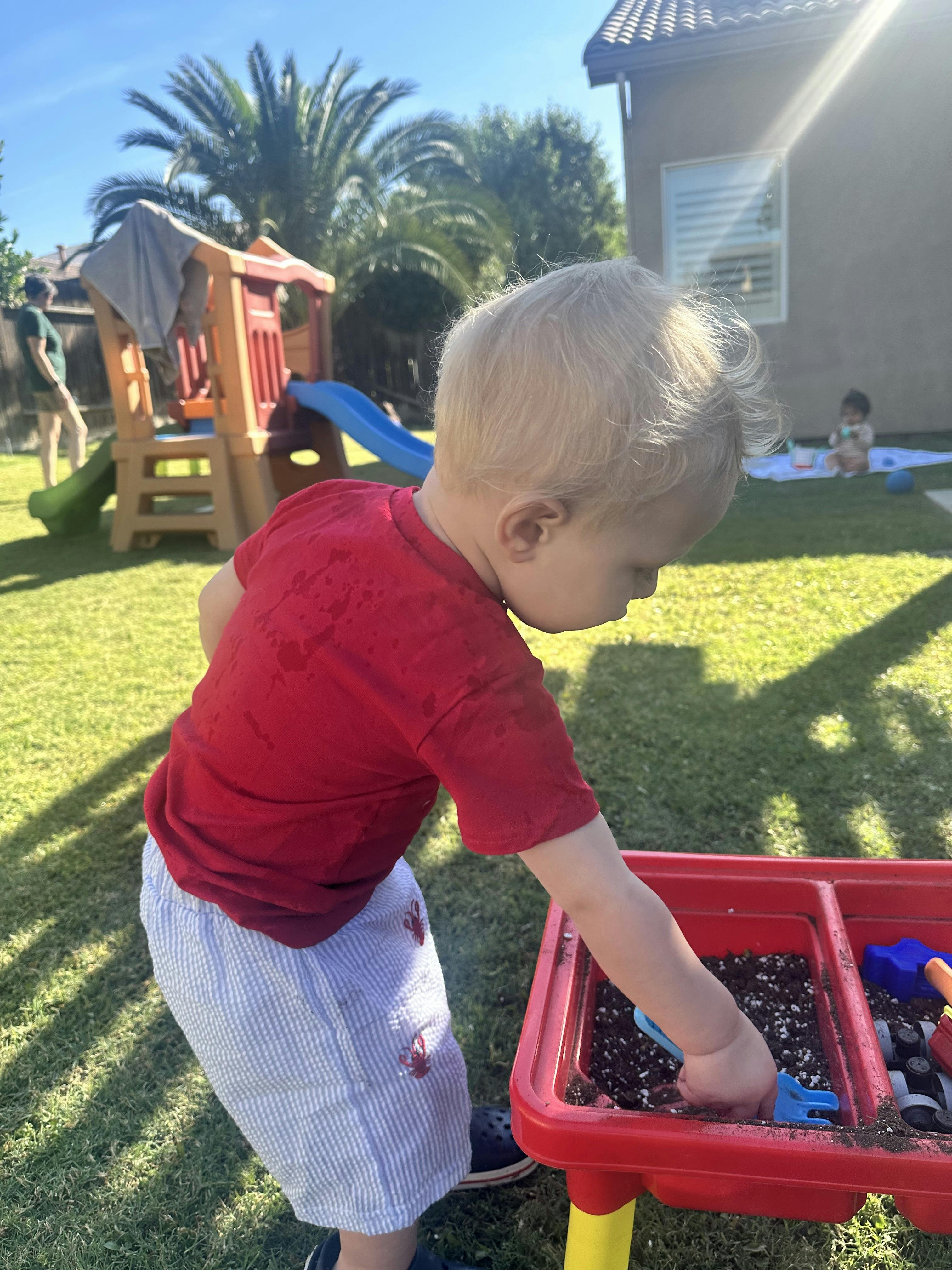 Child playing with soil in a sensory table outdoors