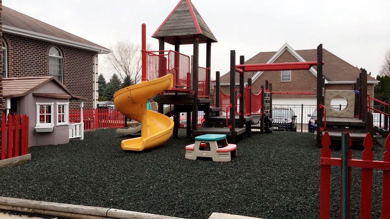 Playground with yellow slide, playhouse, and red fence