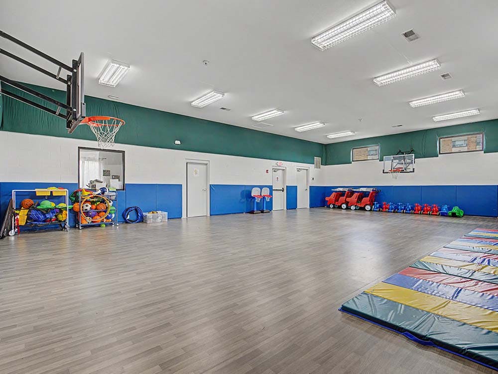 Basketball hoops, sports equipment, and child-sized cars in a gym