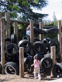 Child playing on a structure made of tires and wooden posts