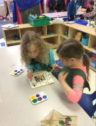 Two children painting at a table in a classroom