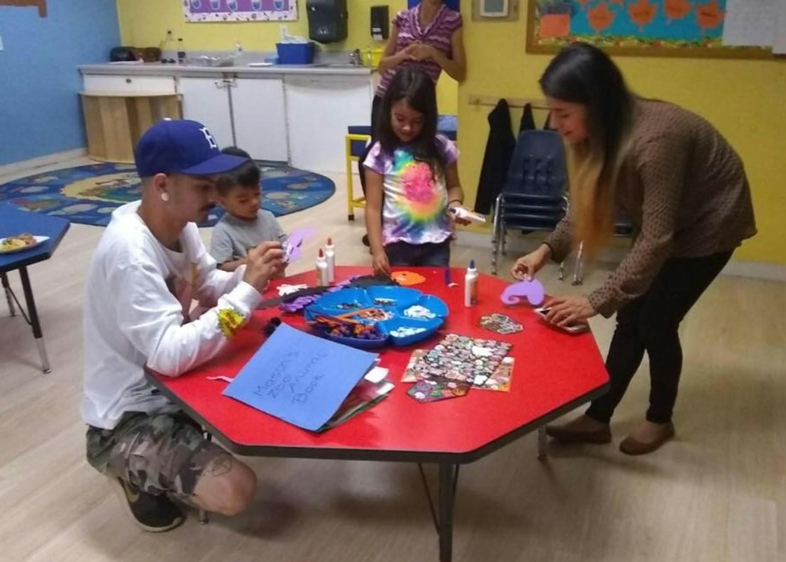 Adults and children doing crafts at a red table