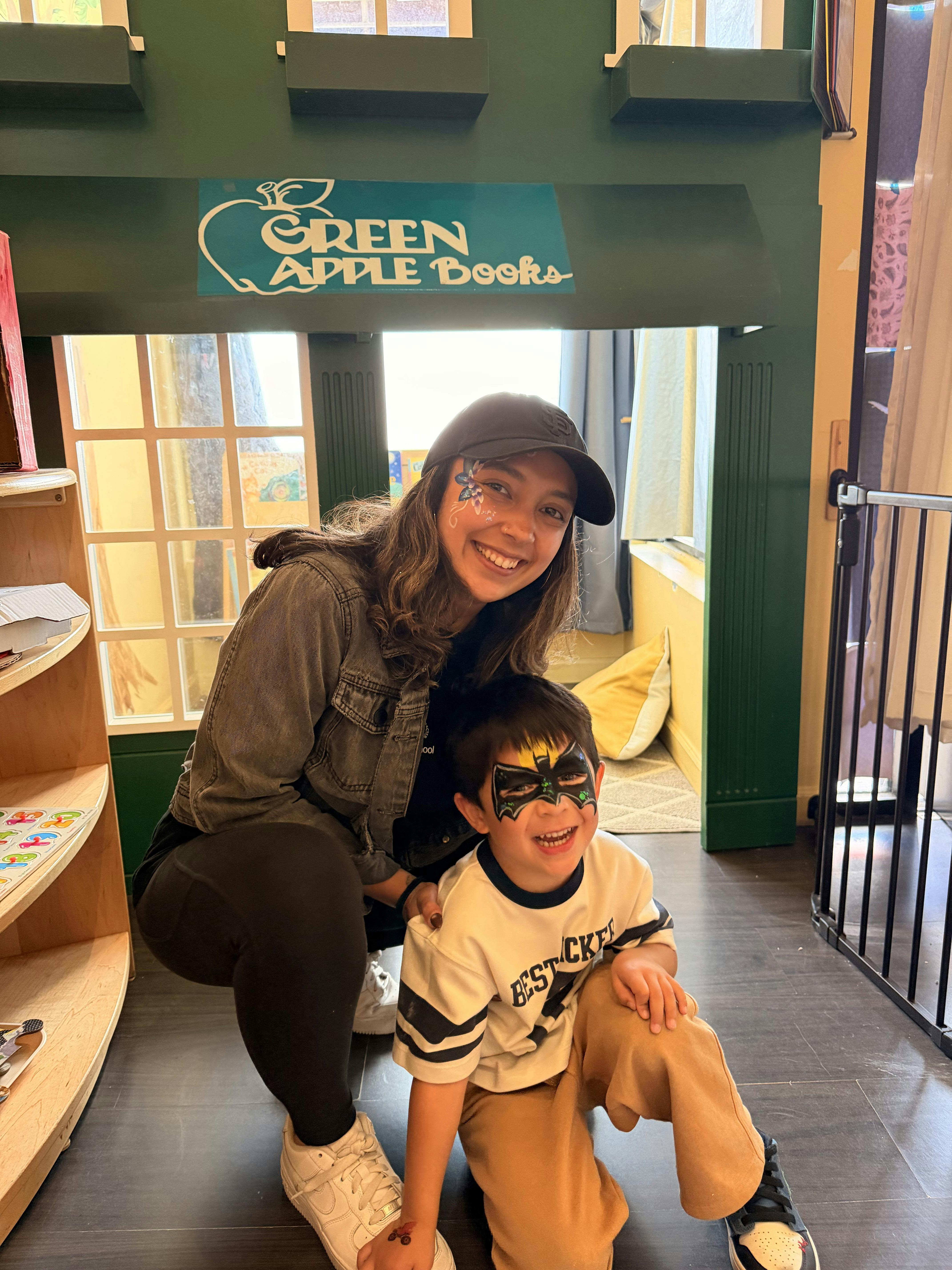 Person with face paint and a child with Batman face paint posing together