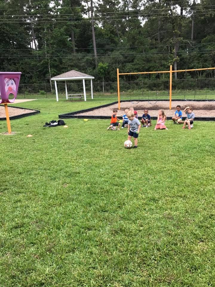 Child playing soccer with other children sitting on the grass