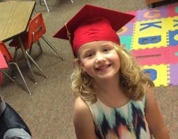 Child wearing a red graduation cap