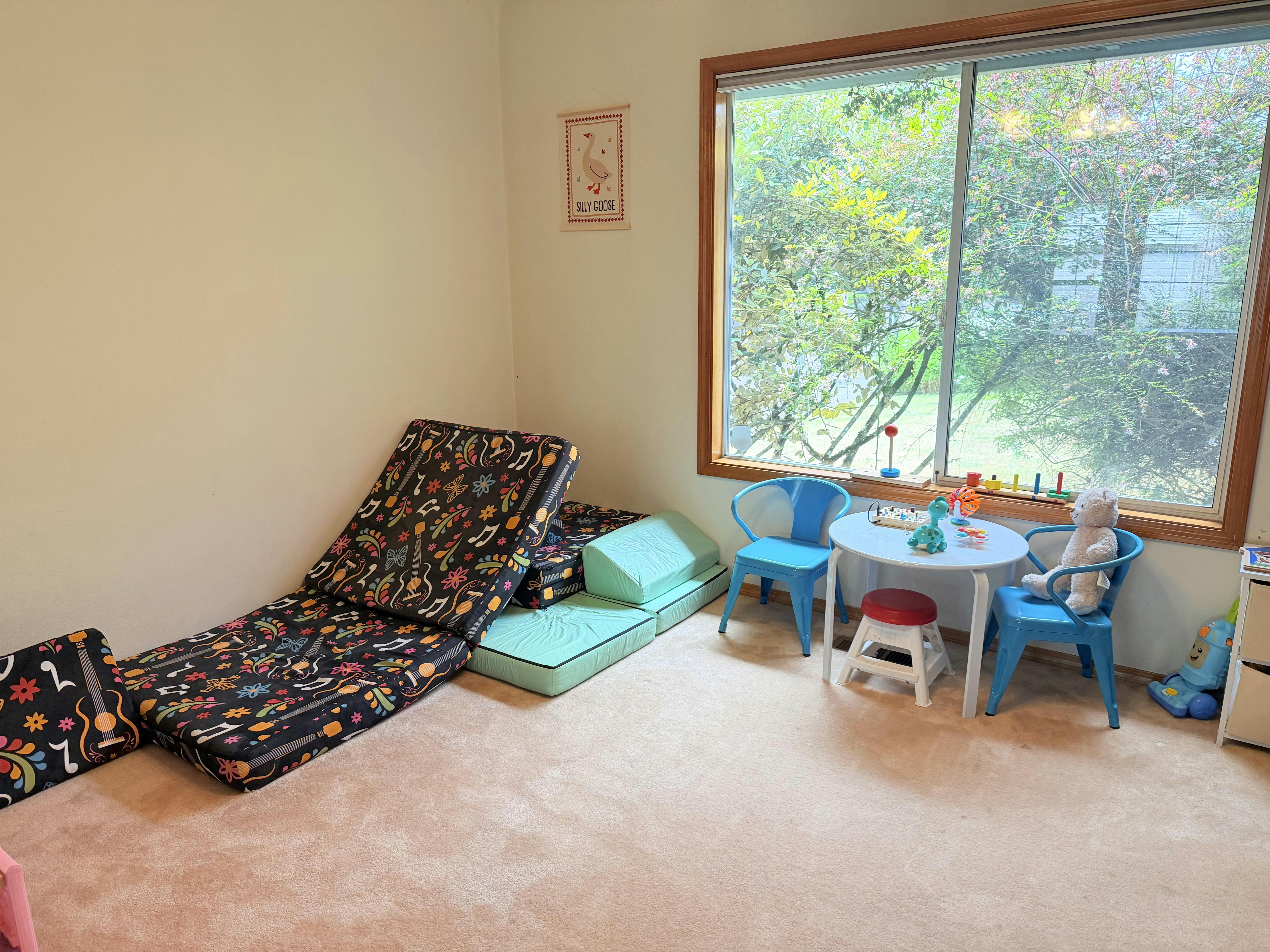 Children's playroom with foam play couches and a small table set by a window