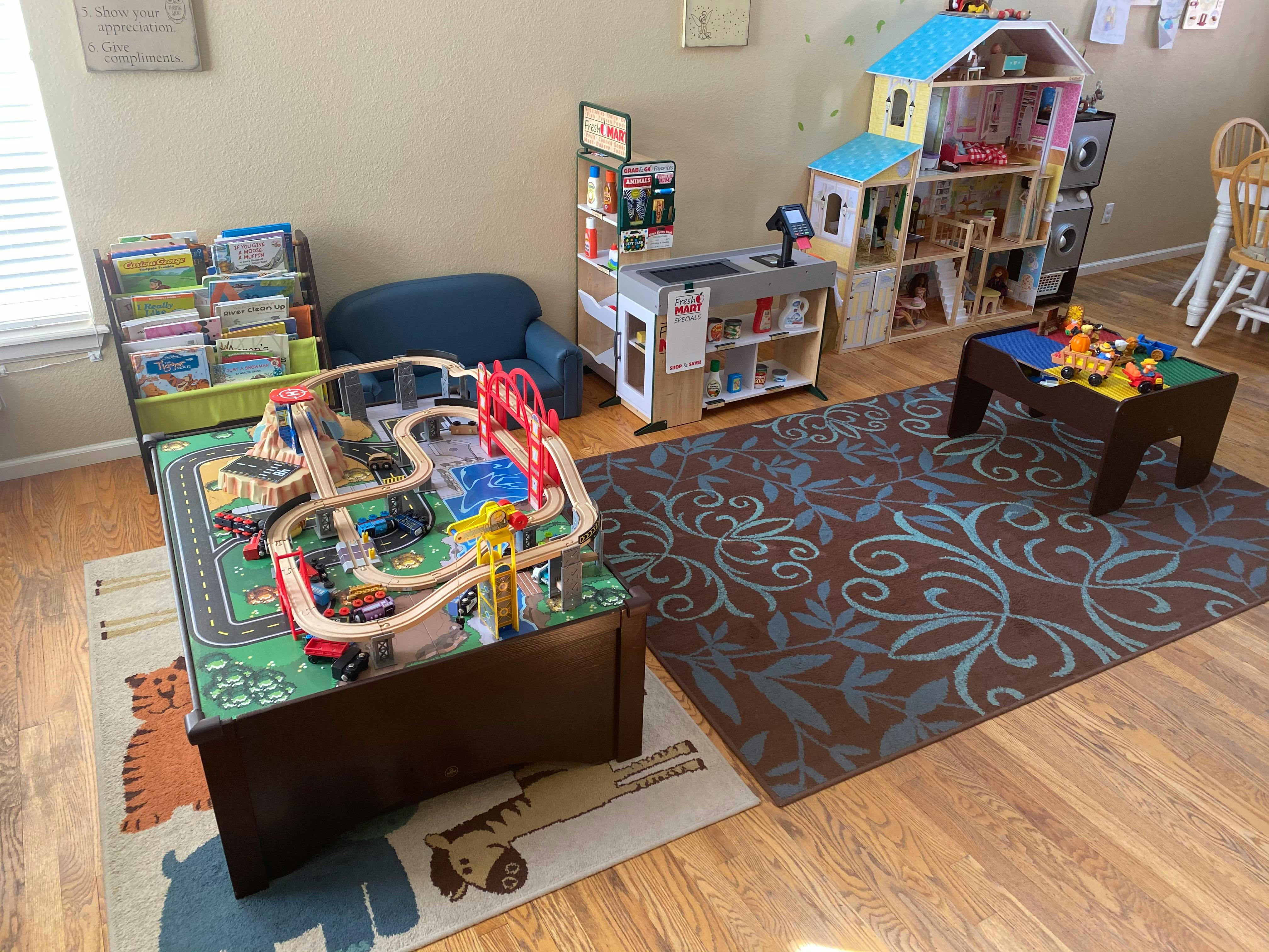 Playroom with a train table, dollhouse, and other toys