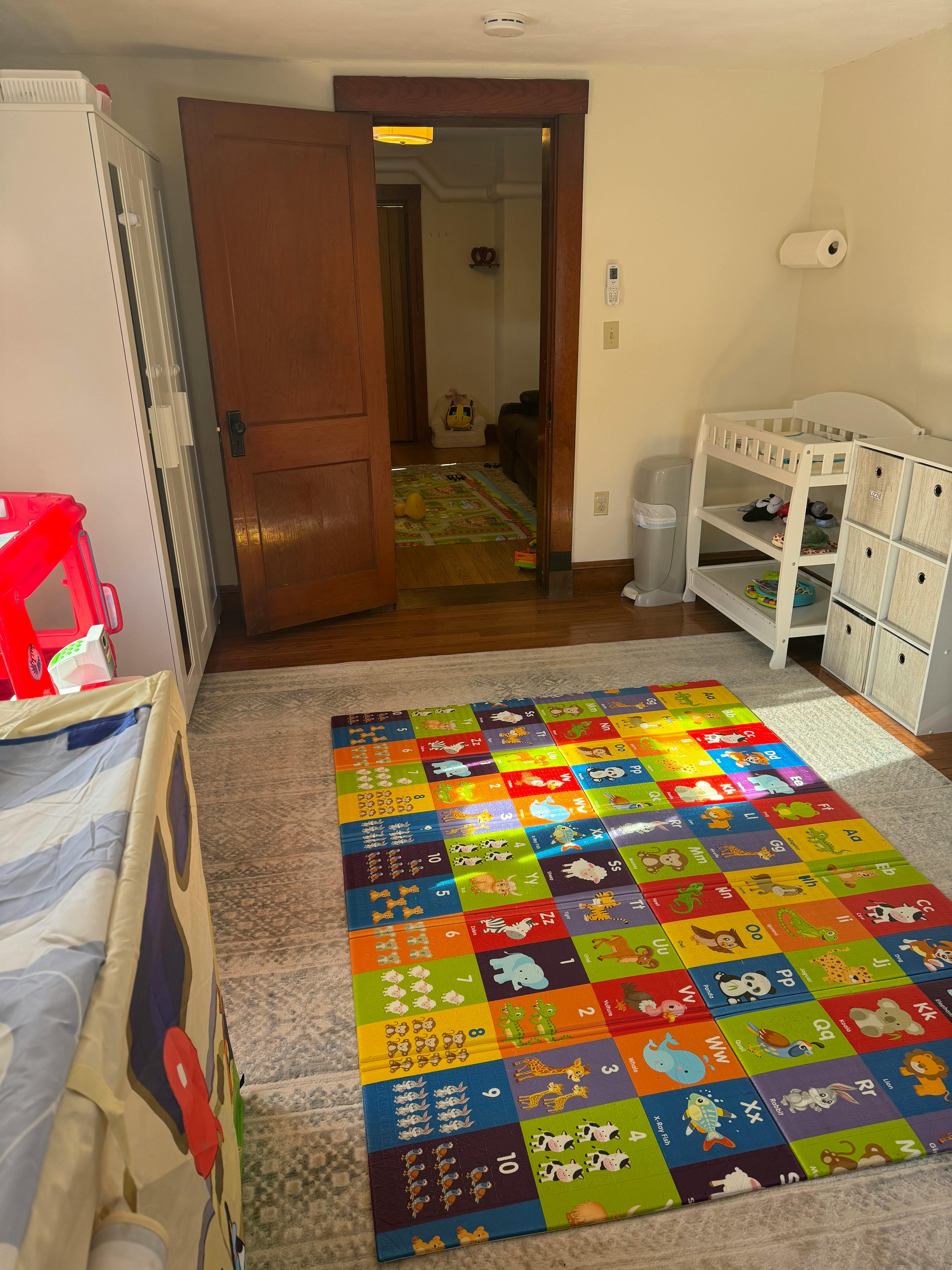 Colorful play mat on a rug in a room with an open door