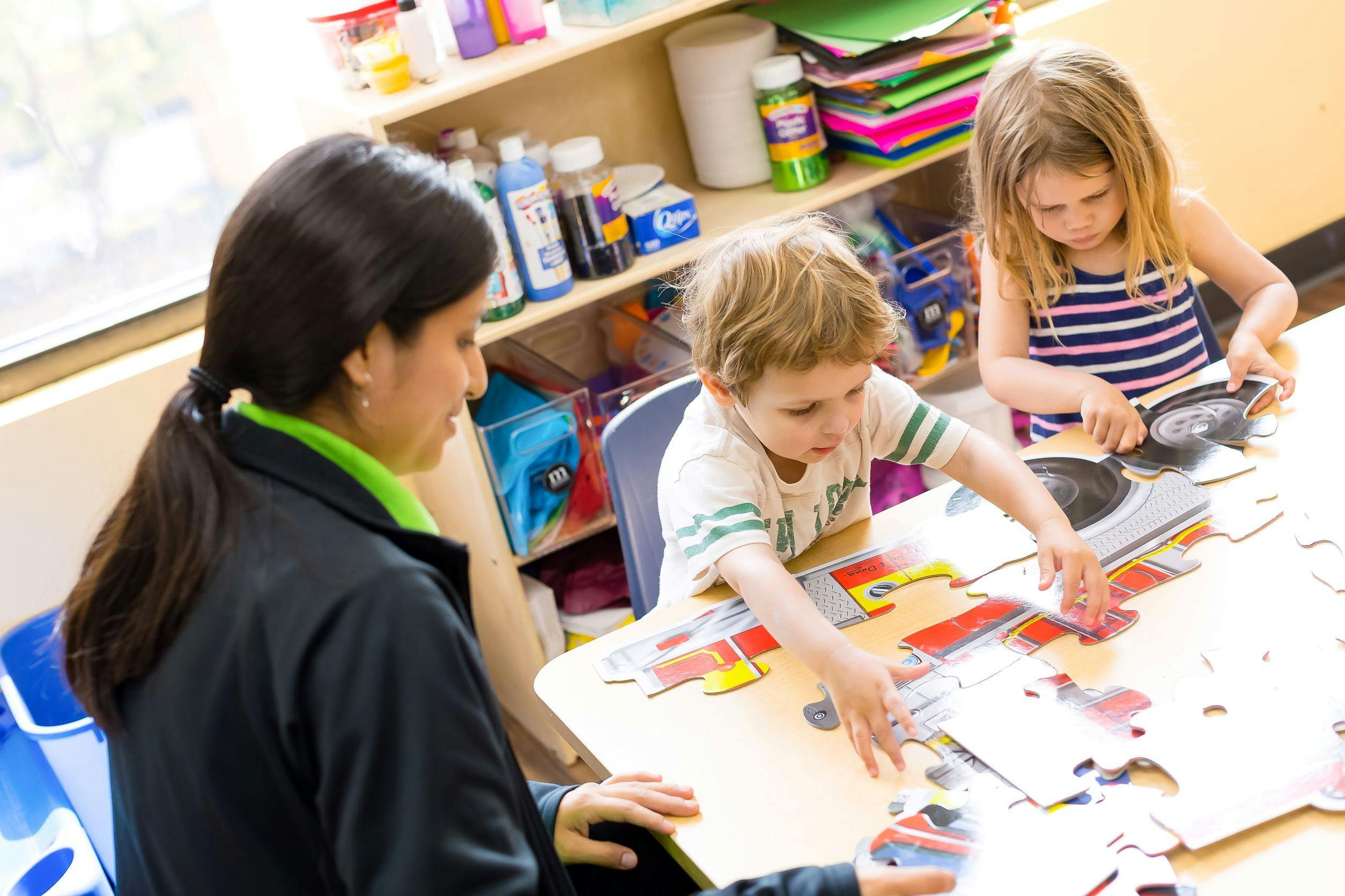 Person and two children assembling puzzles at a table