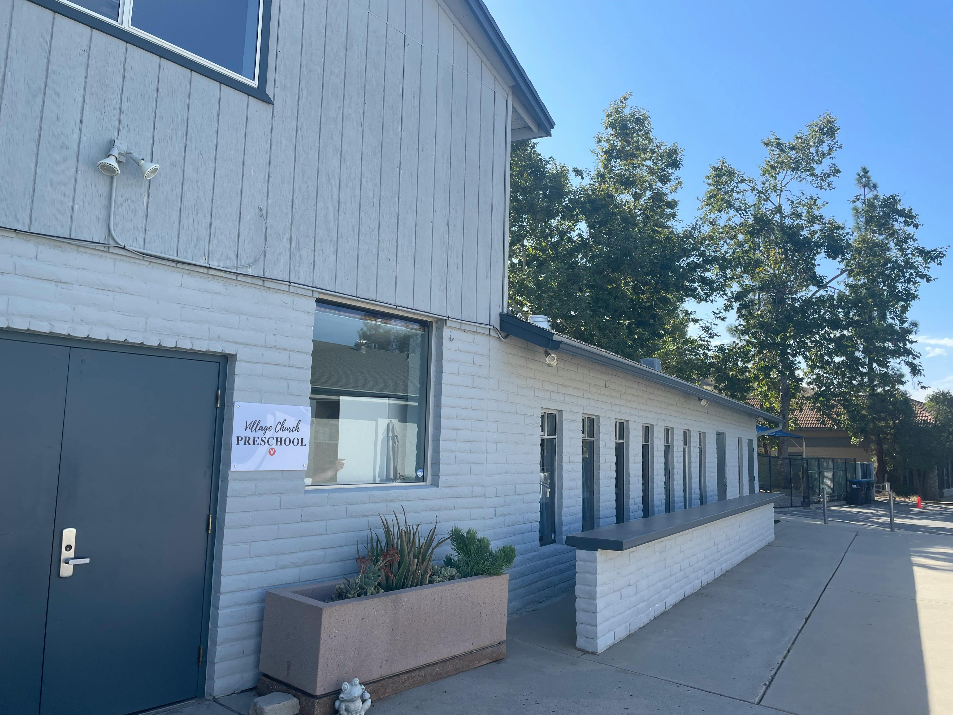 Exterior of a building with a dark door and a sign that says "Preschool"