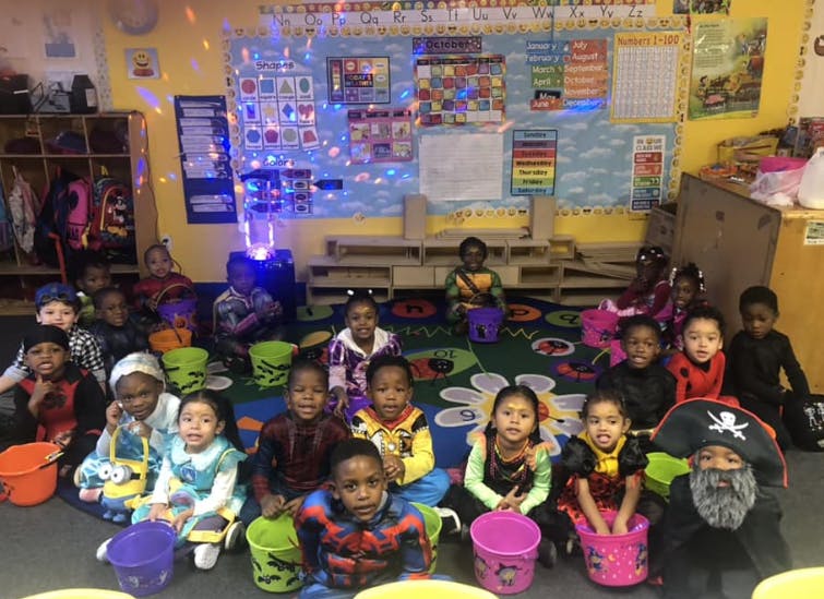 Children in costumes holding buckets in a classroom