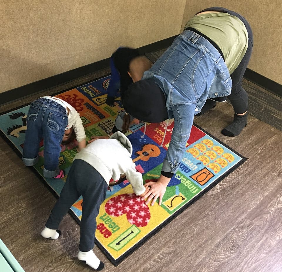 Person and two children bending over a colorful rug