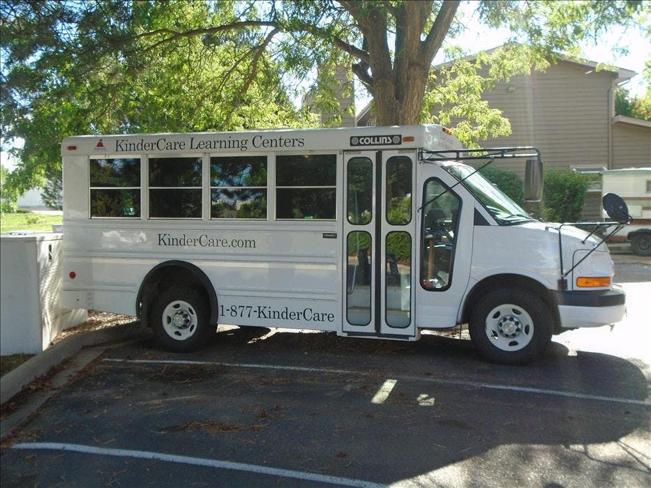 A white KinderCare school bus parked in a lot