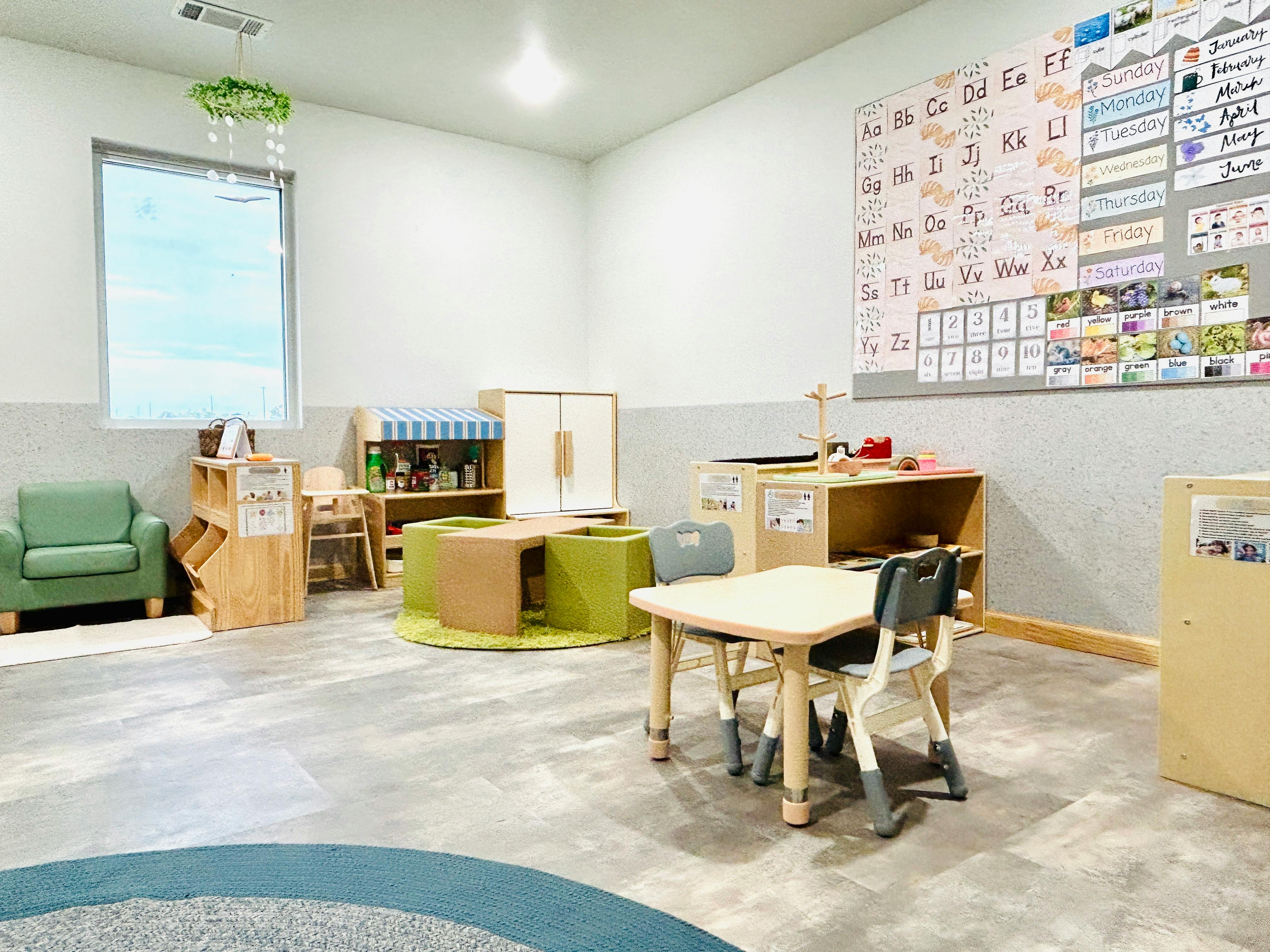 Empty classroom with small tables and chairs, and learning materials on walls