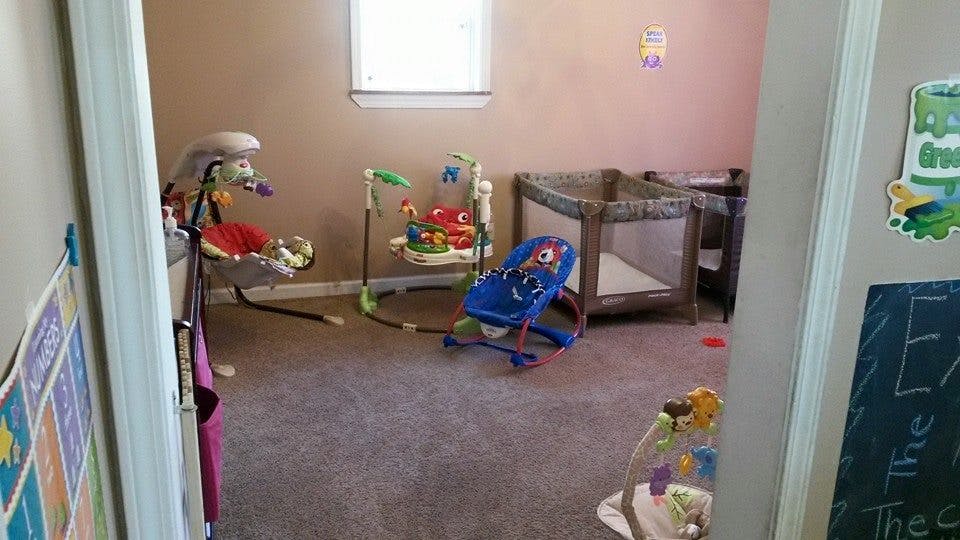 Baby bouncer, play mat, and crib in a room