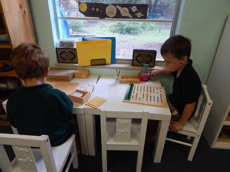 Two children working at small desks in a classroom