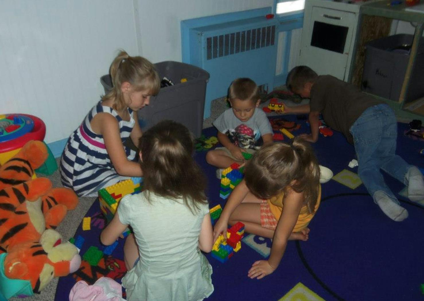 Children playing with colorful building blocks on a blue mat