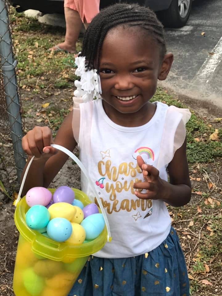 Child holding a bucket of colorful plastic eggs