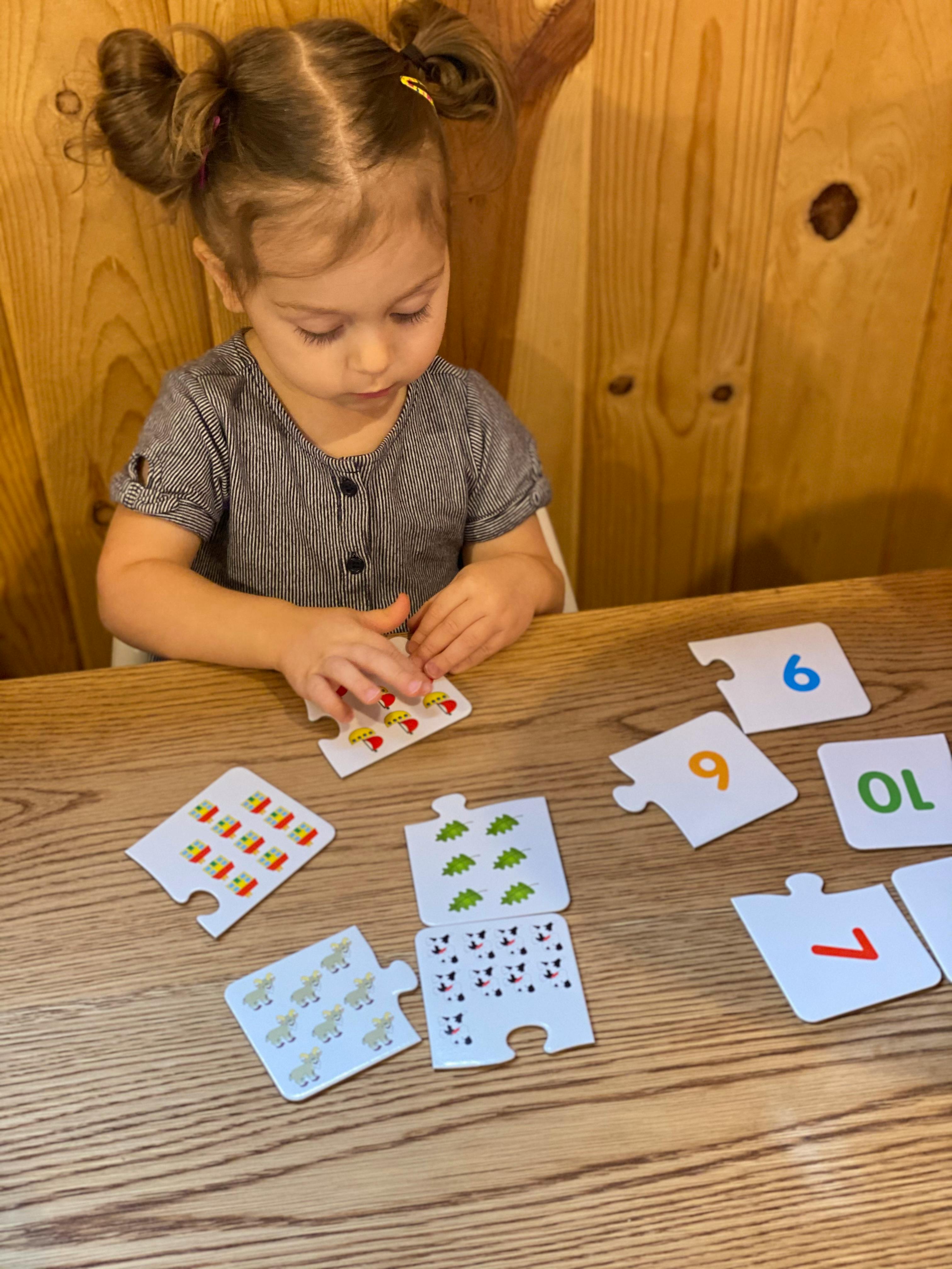 Child playing with number puzzle pieces on a wooden table