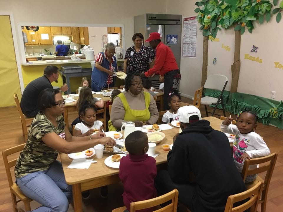Adults and children eating at tables in a room