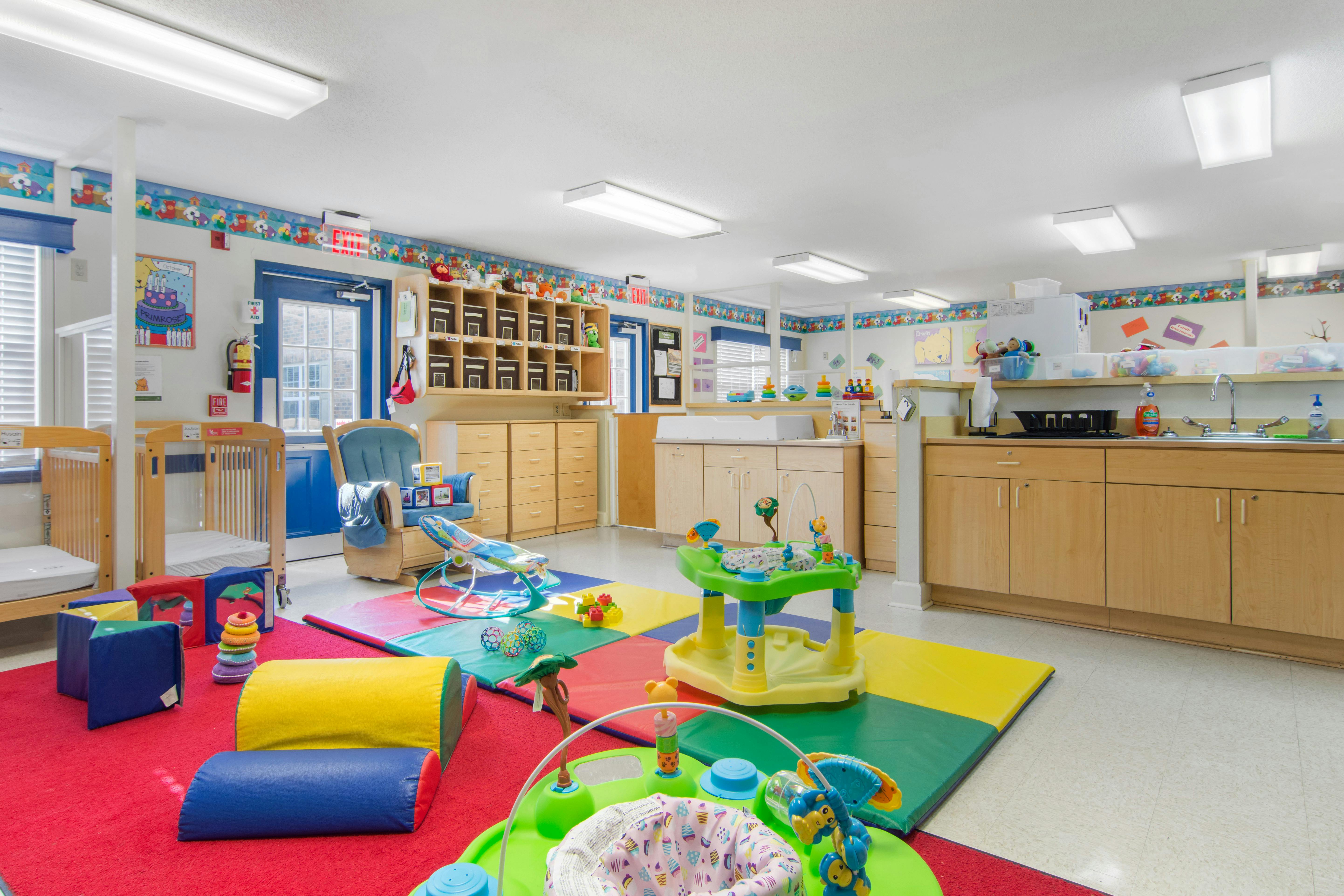 Childcare room with play mats, cribs, and changing tables