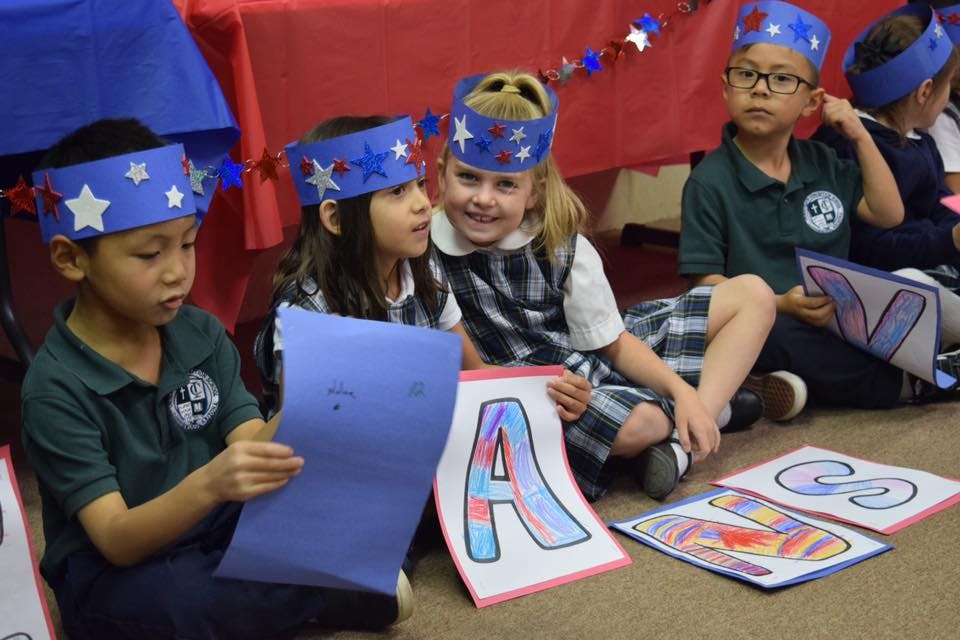 Children in star crowns holding papers and letter cutouts