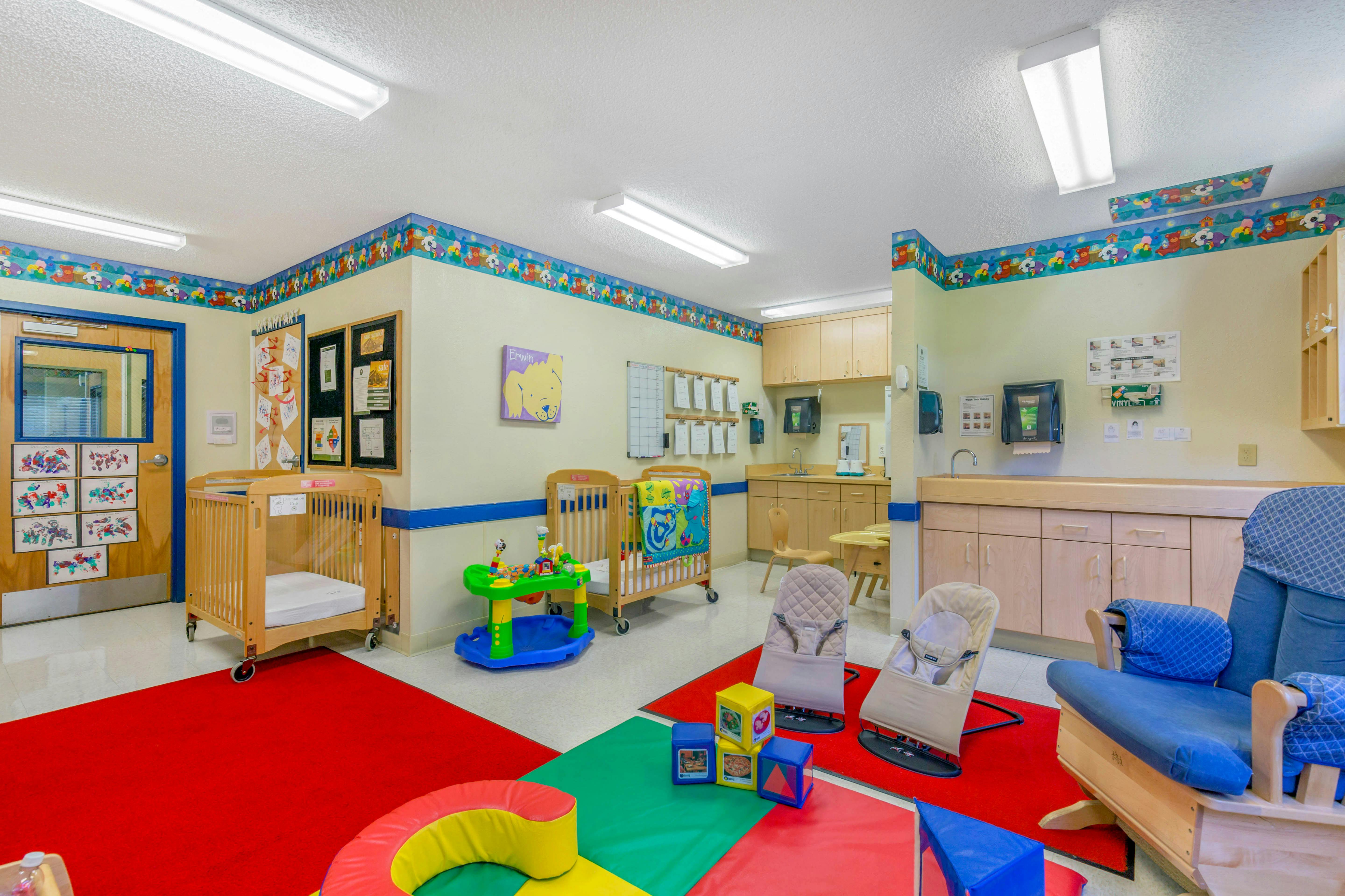 A childcare center with multiple cribs, a red carpet, and changing stations