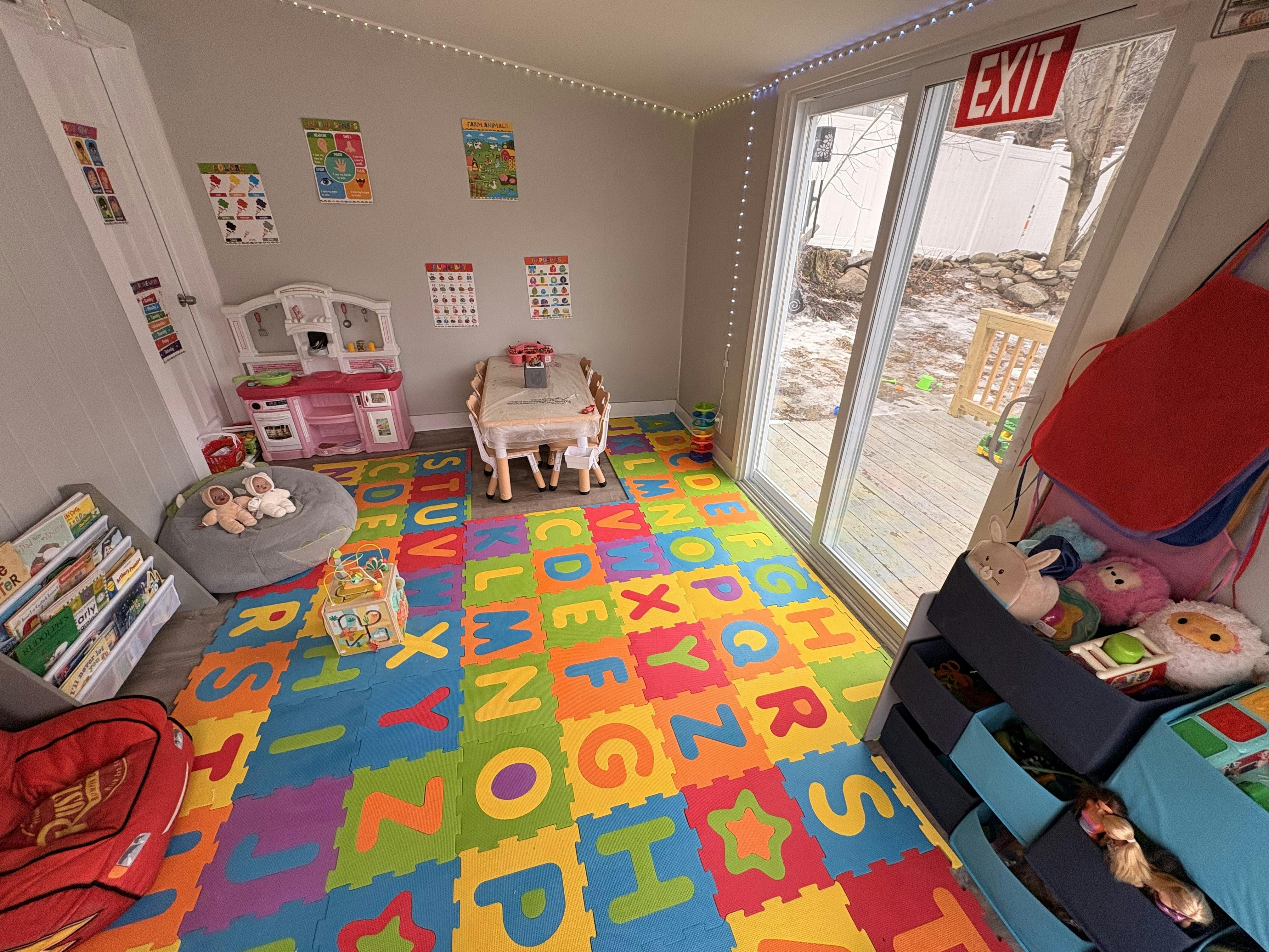 playroom with alphabet floor mats, toy kitchen, and small table and chairs