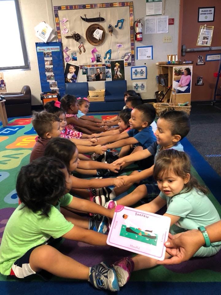 Children sitting in a circle holding hands in a classroom